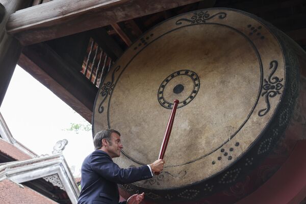 الرئيس الفرنسي إيمانويل ماكرون، يقرع الطبل في معبد "فان ميو"، خلال مأدبة غداء مع الأمين العام للحزب الشيوعي الفيتنامي تو لام، خلال أول زيارة رسمية لماكرون إلى البلاد، هانوي، فيتنام - سبوتنيك عربي