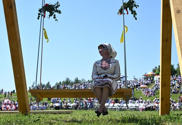 فتاة تجلس على الأرجوحة وتشاهد أحد العروض خلال مهرجان الثقافة "ماري سيميك" في قرية بوتشينوك كوتشوك، مقاطعة كوكمور. - سبوتنيك عربي