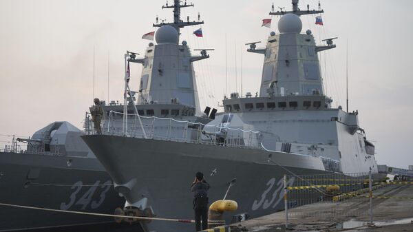 صحفي يلتقط صورة للفرقاطتين التابعين للبحرية الروسية بطل روسيا ألدار تسيدينجابوف، على اليمين، وريزكي، الراسيتين في ميناء تانجونج بريوك في جاكرتا في إندونيسيا - سبوتنيك عربي