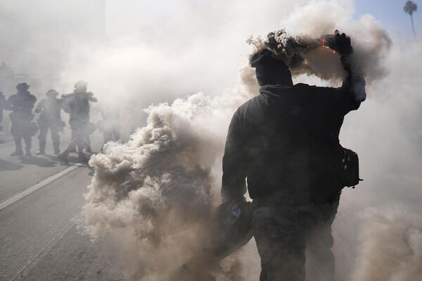 متظاهر يلقي قنبلة دخان على الطريق السريع 101 بالقرب من مركز الاحتجاز. - سبوتنيك عربي