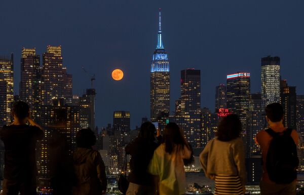 السكان يلتقطون صورًا لـ&quot;قمر الفراولة&quot; المكتمل خلف أفق مانهاتن ومبنى &quot;إمباير ستيت&quot; في مدينة نيويورك، الولايات المتحدة الأمريكية - سبوتنيك عربي