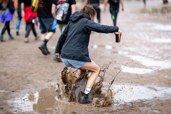 زائر مهرجان "روك إم بارك"يقفز فوق بركة ماء في ألمانيا - سبوتنيك عربي