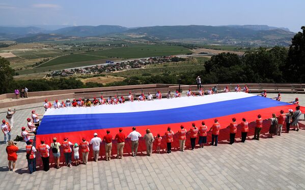 سكان مدينة سيفاستوبول يفرشون العلم الروسي بطول 200 متر على جبل سابون في يوم روسيا. - سبوتنيك عربي