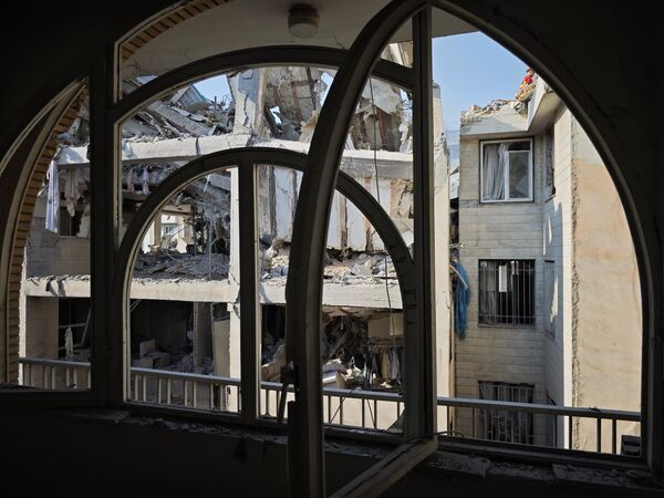 ينظر الناس إلى الأضرار التي لحقت بالمباني بعد الغارات الجوية الإسرائيلية في 13 يونيو 2025 في طهران، إيران. - سبوتنيك عربي