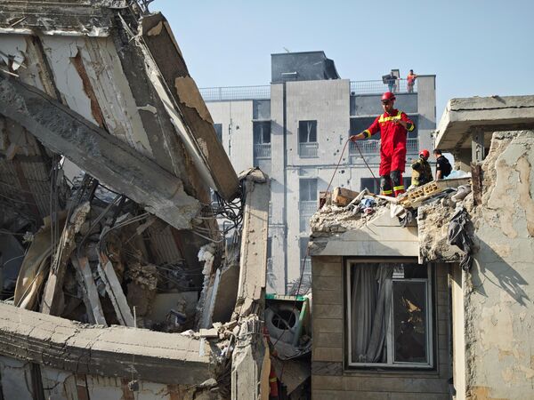 ينظر الناس إلى الأضرار التي لحقت بالمباني بعد الغارات الجوية الإسرائيلية في 13 يونيو 2025 في طهران، إيران. - سبوتنيك عربي