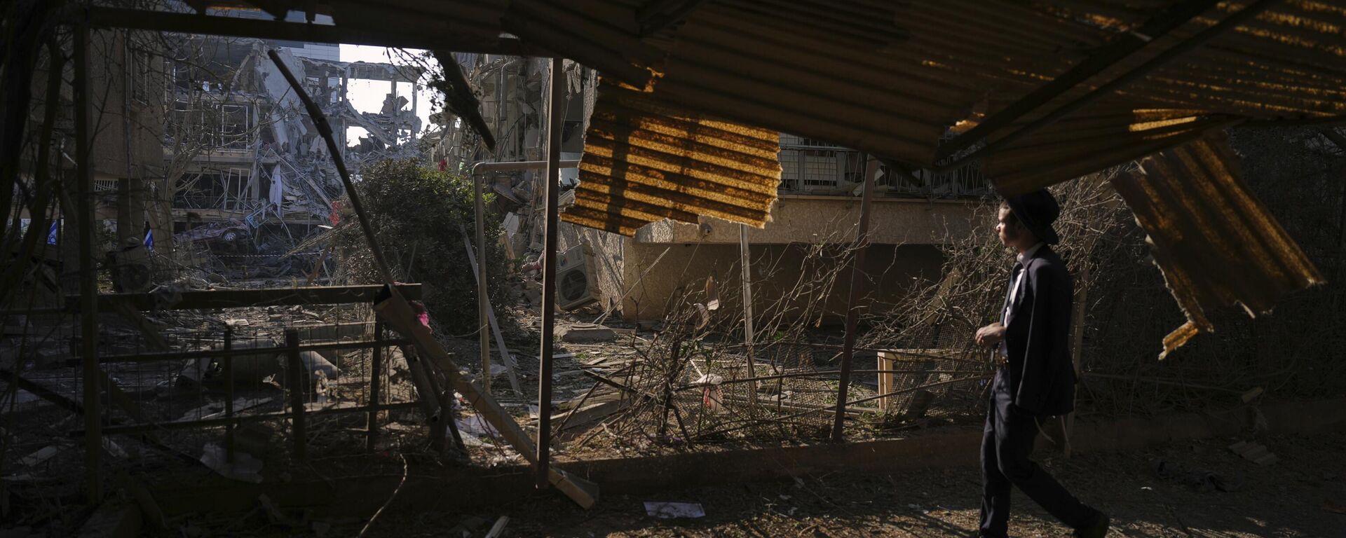 شخص ينظر إلى مبنى سكني مدمر أصيب بصاروخ أطلق من إيران، في رامات جان، بالقرب من تل أبيب، إسرائيل، يوم السبت 14 يونيو 2025. - سبوتنيك عربي, 1920, 15.06.2025