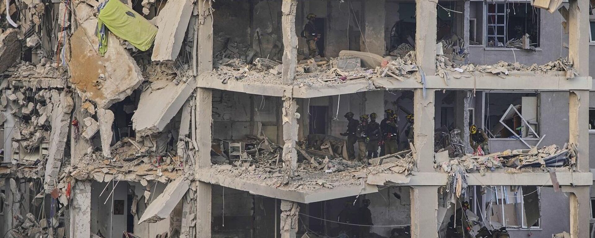 قوات الأمن الإسرائيلية تتفقد مبنى مدمرا أصيب بصاروخ أطلق من إيران، بالقرب من تل أبيب، إسرائيل، 15 يونيو/ حزيران 2025. - سبوتنيك عربي, 1920, 24.06.2025