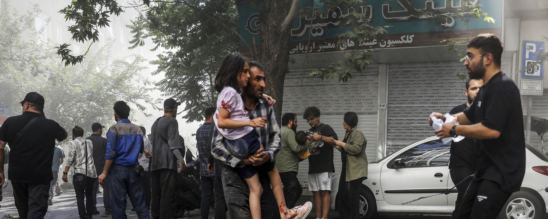 رجل يحمل فتاة مصابة بعد انفجار في وسط طهران جراء الضربات الإسرائيليىة على إيران. - سبوتنيك عربي, 1920, 17.06.2025