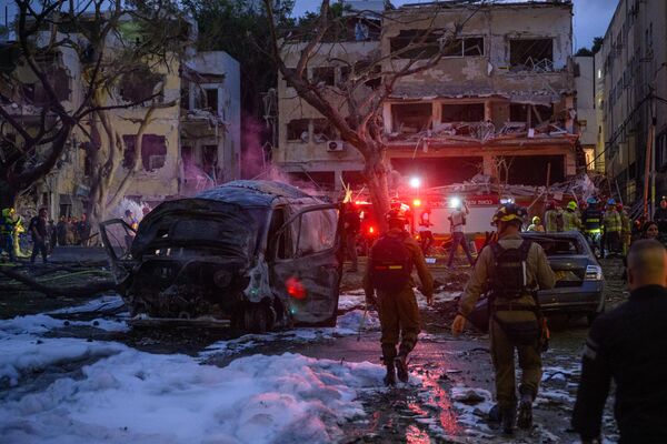 رجال الإنقاذ والأمن الإسرائيليون يتفقدون ويطهرون المباني والمنطقة التي ضربها الصاروخ الإيراني. - سبوتنيك عربي