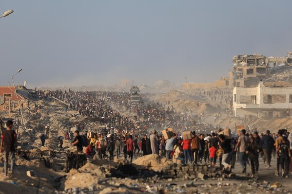 فلسطينيون يحملون صناديق المساعدات الإنسانية، بينما يعاني الناس من الجوع خلال الهجمات الإسرائيلية المستمرة على قطاع غزة - سبوتنيك عربي