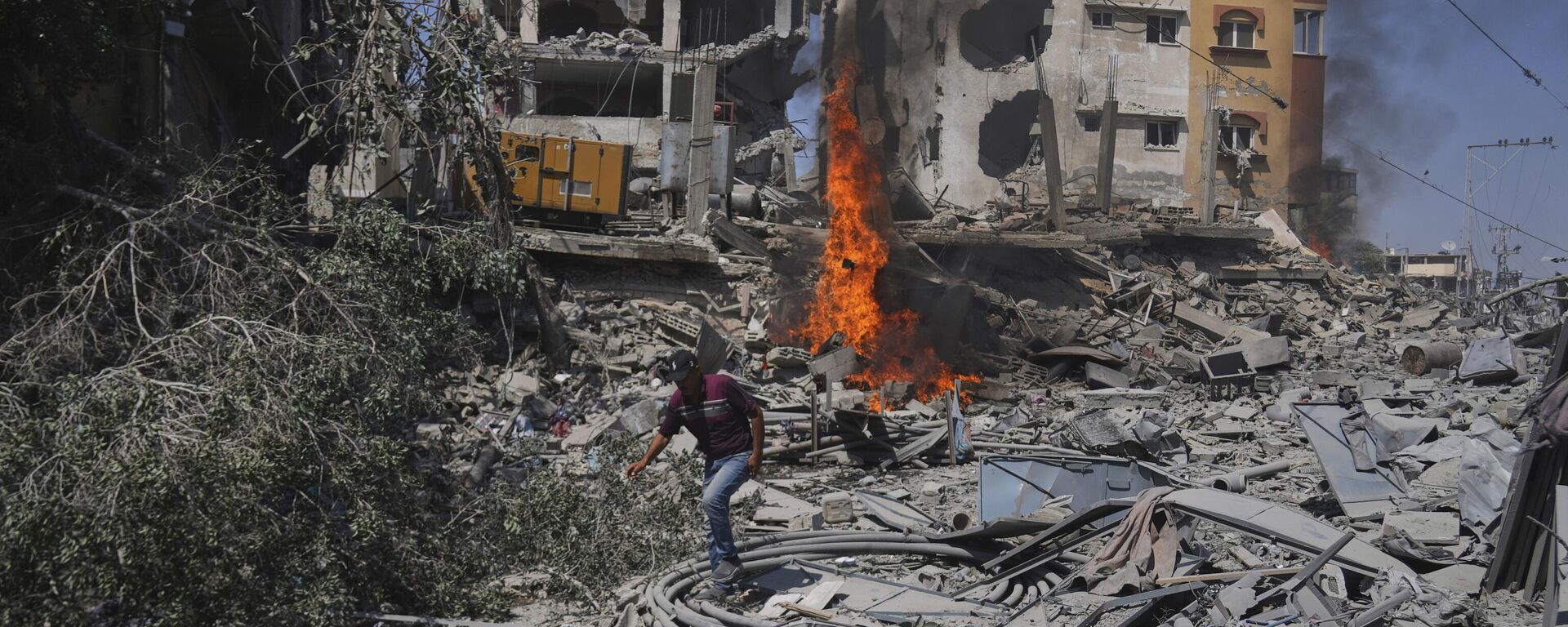 فلسطيني يمشي بين أنقاض مبنى دمره القصف الإسرائيلي في دير البلح، وسط قطاع غزة - سبوتنيك عربي, 1920, 05.07.2025