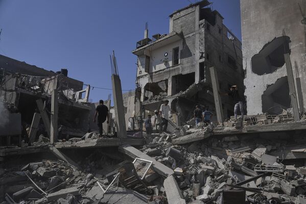 فلسطينيون يتفقدون الأضرار التي لحقت بمنزل دمره القصف الإسرائيلي في دير البلح، وسط قطاع غزة - سبوتنيك عربي