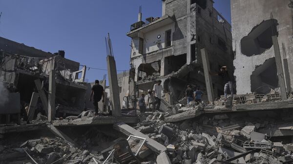 فلسطينيون يتفقدون الأضرار التي لحقت بمنزل دمره القصف الإسرائيلي في دير البلح، وسط قطاع غزة - سبوتنيك عربي