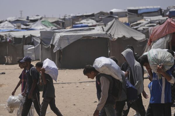 فلسطينيون يحملون أكياسًا من الطعام والمساعدات الإنسانية  في رفح، جنوبي قطاع غزة - سبوتنيك عربي