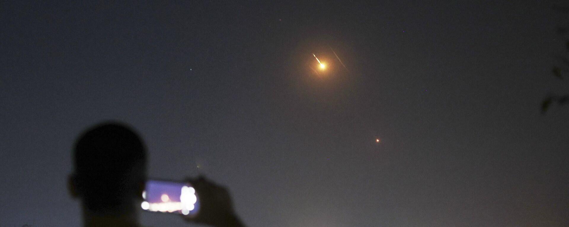 شاب يصور بهاتفه المحمول الصواريخ التي أطلقت من إيران باتجاه إسرائيل فوق الأراضي السورية في دمشق، سوريا، - سبوتنيك عربي, 1920, 22.06.2025