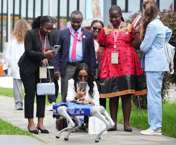 مشاركون من أفريقيا يلتقطون صورة لـ&quot;كلب روبوت&quot; في منتدى بطرسبورغ الاقتصادي الدولي لعام 2025. - سبوتنيك عربي