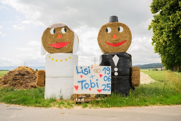 لفتت شخصيات من القش تشبه عروسين الانتباه إلى حفل زفاف ليزي وتوبي في 19 يونيو على الطريق السريع الفيدرالي B3 بالقرب من إلتسه في مقاطعة هيلدسهايم. الصورة. - سبوتنيك عربي