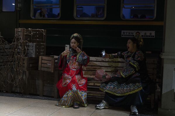 امرأة صينية تستريح على مقعد بالقرب من عربة قطار موضوعة داخل مركز تجاري على طول شارع التسوق وانجفوجينج في بكين، الصين، الخميس 12 يونيو 2025 - سبوتنيك عربي