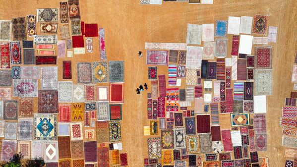 صورة جوية تظهر سجادا منسوجا يدويا مفروشا في الحقول المفتوحة في منطقة دوشيمالتي في أنطاليا، لتنعيم ألوانه طبيعيًا تحت أشعة الشمس، تركيا. - سبوتنيك عربي