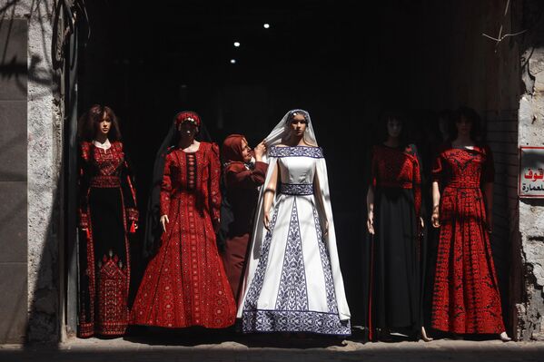 صاحبة متجر فلسطينية تقوم بترتيب الحجاب على عارضات الأزياء أمام متجرها في مدينة غزة، فلسطين. - سبوتنيك عربي