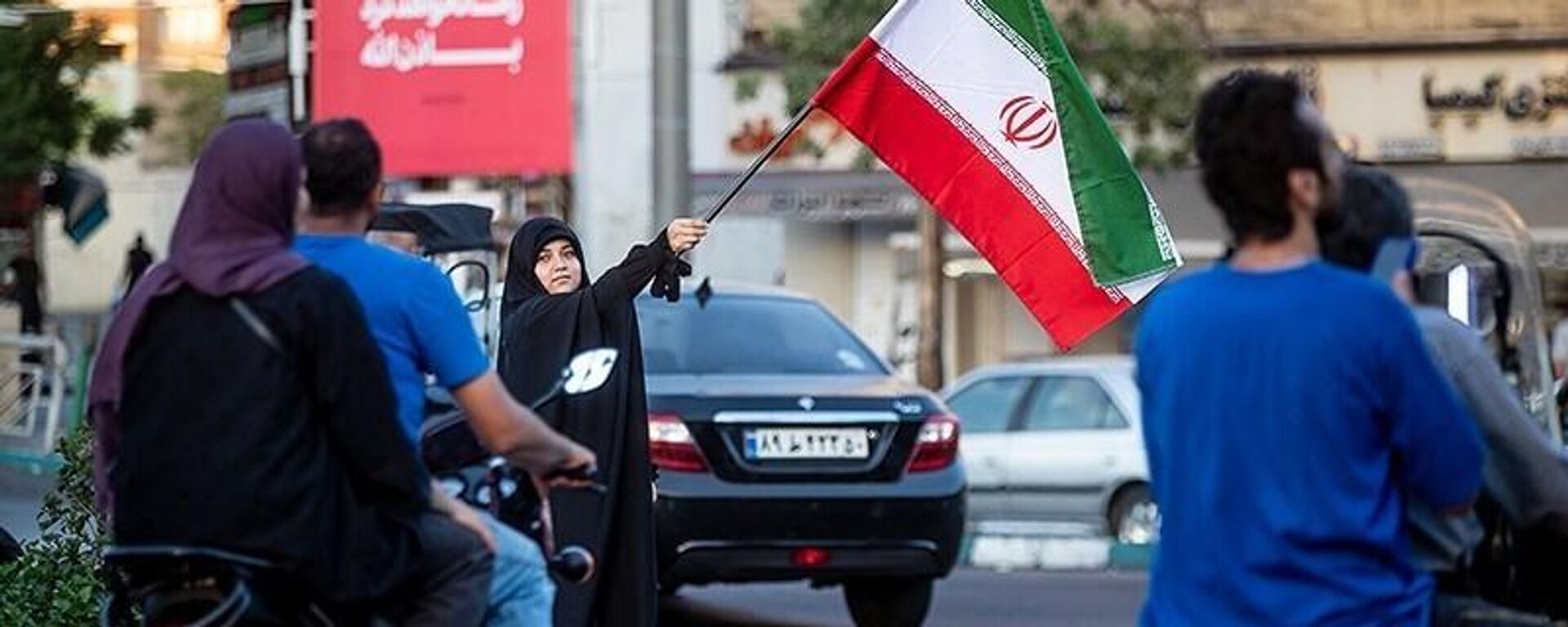 سيدة إيرانية تلوح بعلم إيران وسط الشارع في طهران   - سبوتنيك عربي, 1920, 03.09.2025
