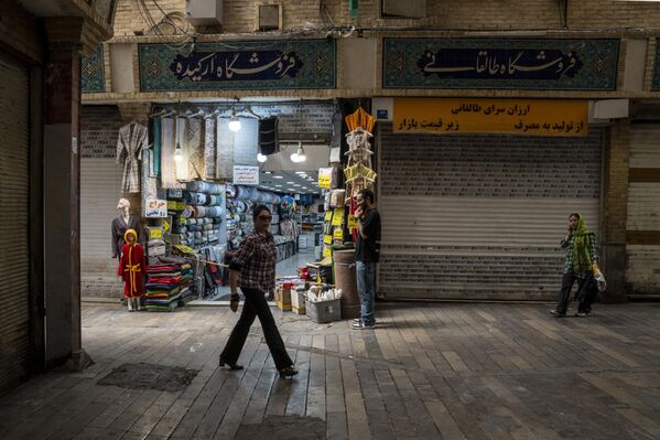 أناس يسيرون في سوق طهران المغلق جزئيًا، بعد الساعات الأولى من شن الولايات المتحدة الأمريكية هجوما على 3 منشآت نووية إيرانية في نطنز وفوردو وأصفهان، ليلة 22 يونيو الجاري - سبوتنيك عربي