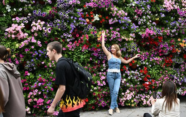 فتاة تلتقط صورة بين أنواع مختلفة من الزهور في أحد شوارع موسكو. - سبوتنيك عربي