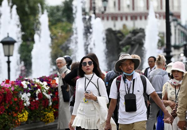 عدد من السياح يتجولون في شوارع موسكو المزينة بورود فصل الصيف . - سبوتنيك عربي