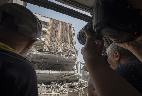 مصورون إيرانيون يلتقطون صورا لمبنى في منطقة سكنية، استهدفه هجوم إسرائيلي غربي العاصمة الإيرانية طهران. - سبوتنيك عربي
