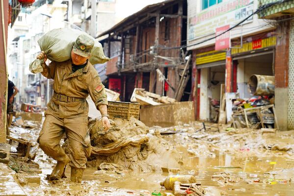  رجل إنقاذ يحمل إمدادات في منطقة متضررة من الفيضانات في مقاطعة كونغجيانغ في الصين. - سبوتنيك عربي