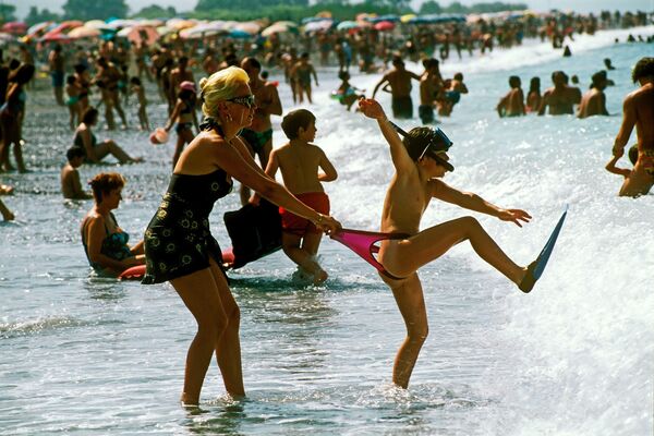 امرأة تحاول الإمساك بطفلها على شاطئ مدينة مارينا دي ماراتي على ساحل البحر التيراني، إيطاليا. - سبوتنيك عربي