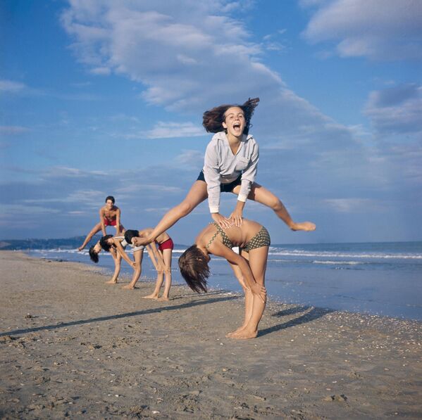 مراهقون يلعبون لعبة القفز فوق بعضهم البعض على الشاطئ. - سبوتنيك عربي
