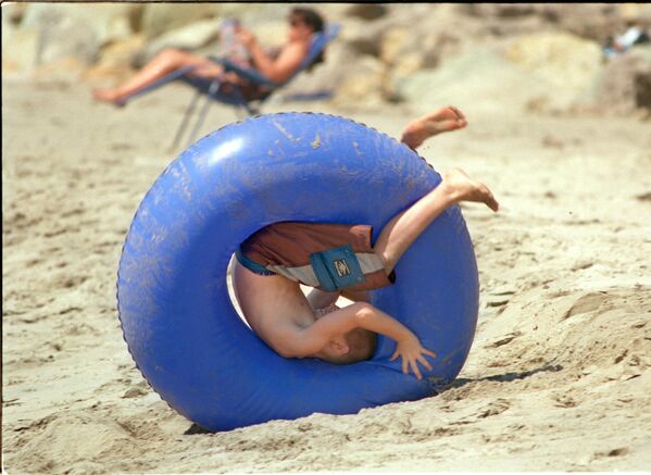 جوش ديل، 11 عاما، من أوجاي، يتدحرج على الرمال داخل أنبوب نحو المحيط في شاطئ إيما وود، فينتورا كاليفورنيا. - سبوتنيك عربي