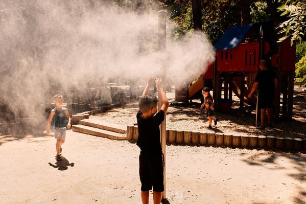 أشخاص يبردون أجسامهم ويستمتعون برذاذ الماء في حديقة "مونتسوريس" خلال موجة الحر في باريس، فرنسا. - سبوتنيك عربي