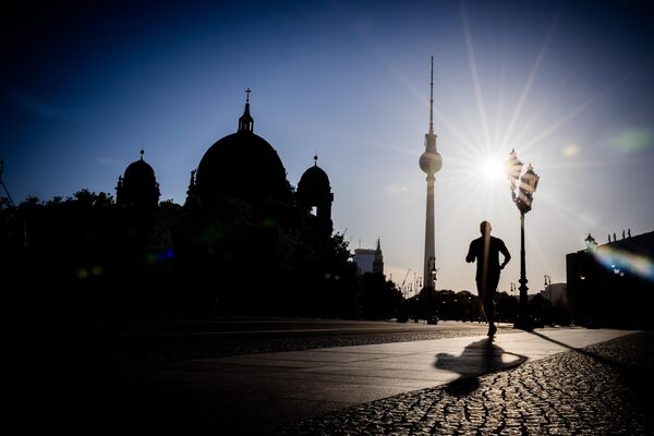عدّاء يركض أمام برج التلفزيون والكاتدرائية في الصباح الباكر في برلين، ألمانيا. - سبوتنيك عربي