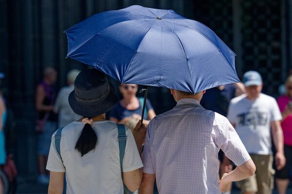 سياح يحمون أنفسهم من أشعة الشمس بمظلة في كولونيا، ألمانيا. - سبوتنيك عربي