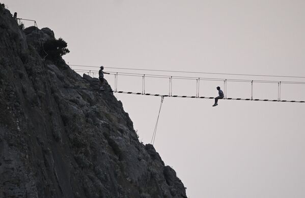 مصطافون يعيشون لحظات من المغامرة أثناء عبورهم سلم معلق في سيميز. - سبوتنيك عربي