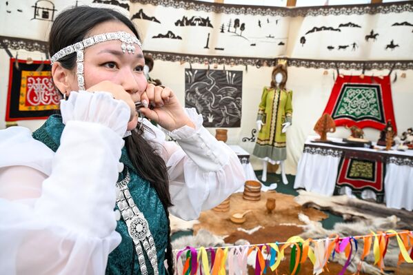 إحدى المشاركات في المهرجان السادس للجمعية الجغرافية الروسية "عجائب روسيا" تعزف على قيثارة الفم في جناح جمهورية ساخا (ياقوتيا) في حديقة زاريادي في موسكو. - سبوتنيك عربي