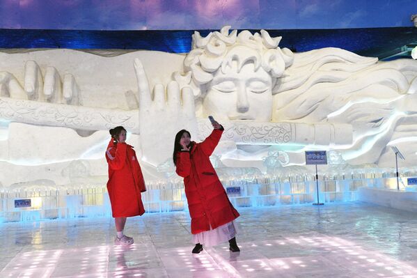 سياح يلتقطون صورة مع منحوتات ثلجية في معرض "صن آيلاند" للفنون الجليدية والثلجية في هاربين، الصين. - سبوتنيك عربي
