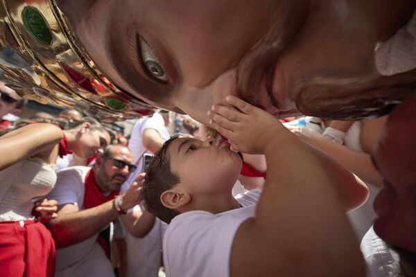 لقطة طريفة لطفل يقبل رأس تمثال كبير في مهرجان" سان فيرمين" في بامبلونا، شمالي إسبانيا - سبوتنيك عربي