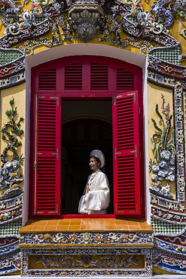 شابة ترتدي زيا تقليديا وتقف أمام نافذة قصر كين ترونغ في فيتنام. - سبوتنيك عربي