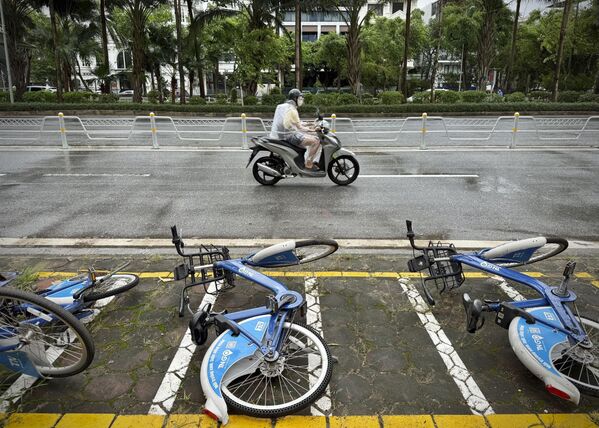 سائق دراجة نارية يقود دراجته بجوار دراجات هوائية سقطت تحت المطر الناجم عن العاصفة الاستوائية "ويفا" في هانوي، فيتنام. - سبوتنيك عربي