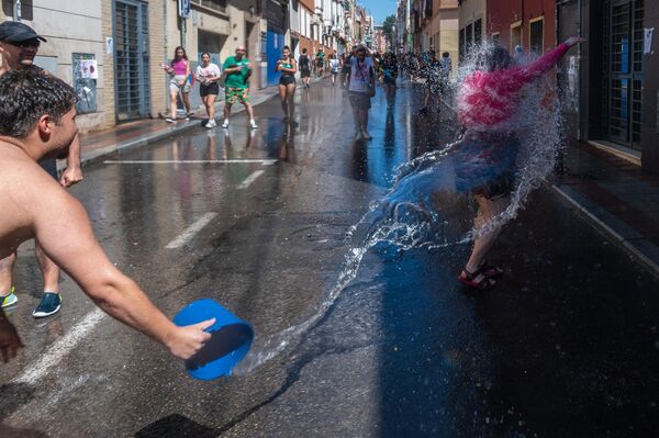 محتفلون يشاركون في معركة المياه الصيفية السنوية المعروفة باسم "باتالا نافال" التي تقام في حي فاليكاس في العاصمة الإسباية مدريد، حيث يتبادلون رشق بعضهم بعضا بالدلاء ومسدسات الماء، بينما يرش الجيران بعضهم البعض بالماء من شرفاتهم. - سبوتنيك عربي