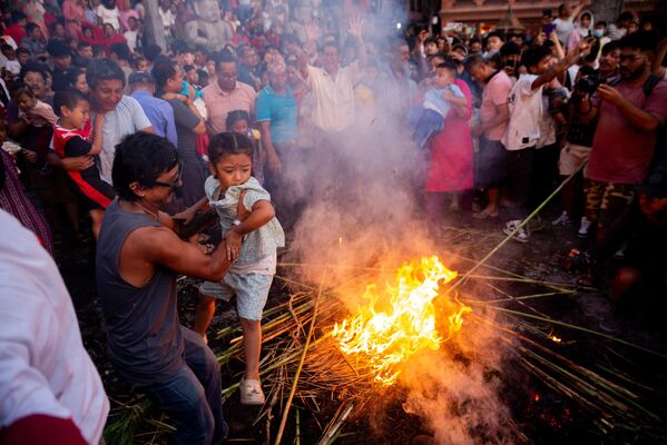 أحد المتعبدين يرفع طفله فوق النار احتفالًا بهزيمة الشيطان الأسطوري غانتاكارنا، ومطاردة الأرواح الشريرة وجلب الحظ السعيد، نيبال. - سبوتنيك عربي
