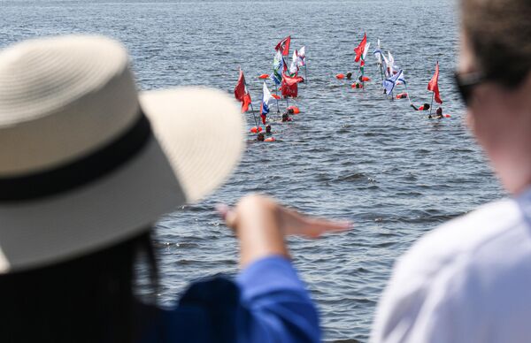 اتحاد السباحة الشتوية يسبح حاملا الأعلام في مياه محطة النهر الشمالي خلال الاحتفال بيوم البحرية. - سبوتنيك عربي