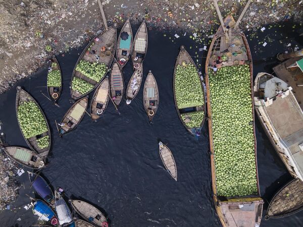 منظر جوي لعدة قوارب تجارية صغيرة تحمل أشخاصًا يفرغون حمولتهم من البطيخ في ميناء دكا النهري القديم على طول نهر بوريجانجا في دكا، بنغلاديش. - سبوتنيك عربي