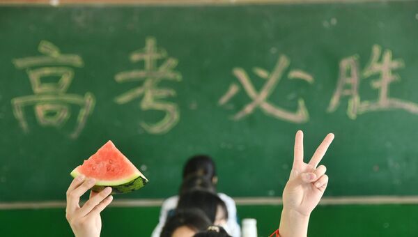 ثلاثة طلاب من الصف الثالث الثانوي يُظهرون البطيخ الذي حصلوا عليه، ويُظهرون لفتاتهم الرابحة لتشجيع أنفسهم. - سبوتنيك عربي