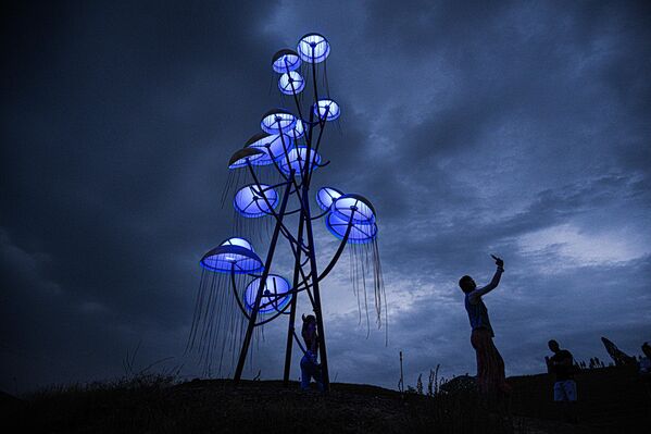 زوار بالقرب من هيكل فني في موقع مهرجان الشباب العاملين في الثقافة والفنون "تافريدا. آرت-2025"، في خليج "كابسيل" بجمهورية القرم الروسية - سبوتنيك عربي