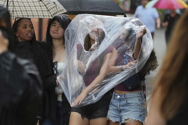 الناس يضعون كيسًا بلاستيكيًا أثناء سيرهم تحت المطر في المدينة القديمة في تالين، إستونيا. - سبوتنيك عربي