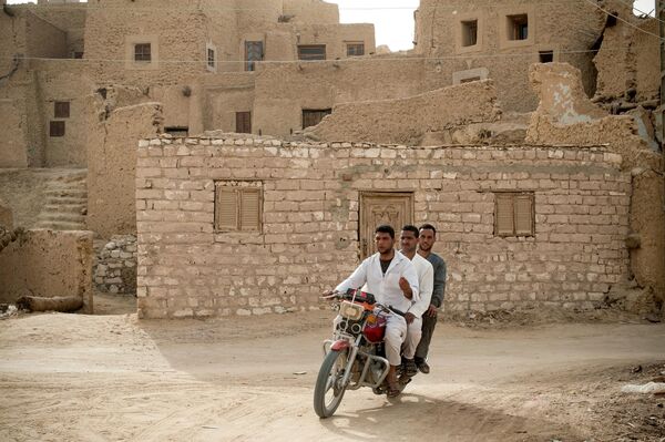 ثلاثة رجال مصريين يركبون دراجة نارية قرب قلعة شالي. - سبوتنيك عربي